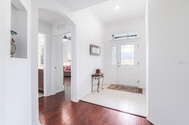 entryway with arched walkways, visible vents, ceiling fan, wood finished floors, and baseboards