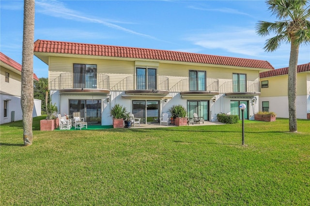 back of house featuring a lawn, a balcony, and a patio