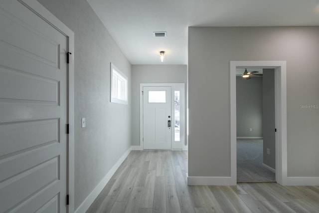 foyer entrance featuring baseboards, ceiling fan, and light wood finished floors