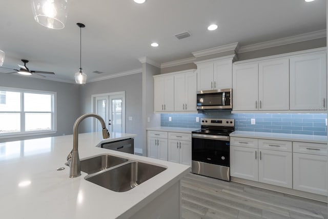 kitchen featuring visible vents, a sink, light countertops, appliances with stainless steel finishes, and decorative light fixtures