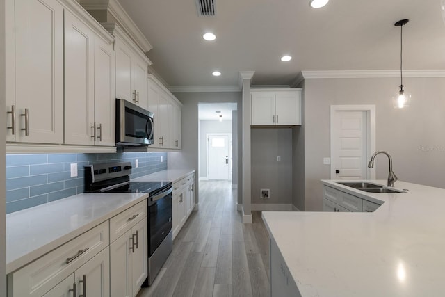 kitchen with ornamental molding, visible vents, appliances with stainless steel finishes, and a sink