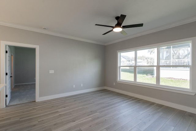 spare room with light wood finished floors, a ceiling fan, crown molding, and baseboards