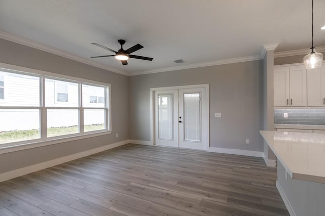 unfurnished living room with baseboards, wood finished floors, a ceiling fan, and ornamental molding