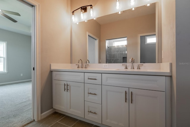 bathroom featuring double vanity, a ceiling fan, baseboards, and a sink