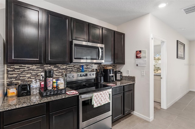 kitchen with backsplash, dark stone counters, a textured ceiling, stainless steel appliances, and light tile patterned flooring