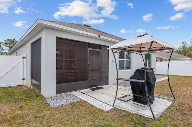 back of property with a gazebo, a sunroom, a patio area, and a yard