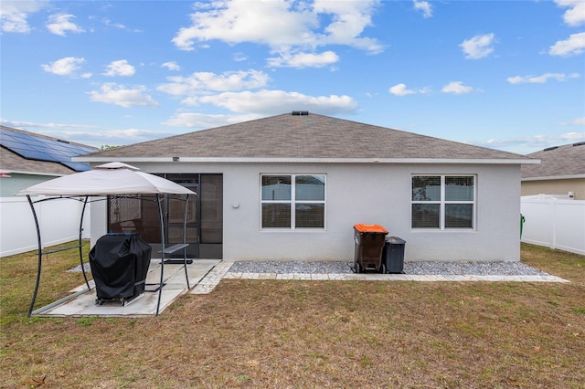 back of property with a gazebo, a patio area, and a lawn