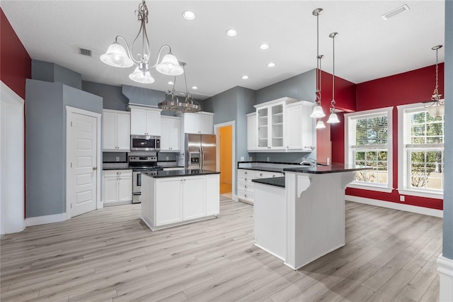 kitchen with appliances with stainless steel finishes, hanging light fixtures, and white cabinetry