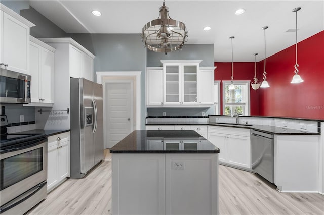 kitchen featuring stainless steel appliances, white cabinetry, sink, and hanging light fixtures