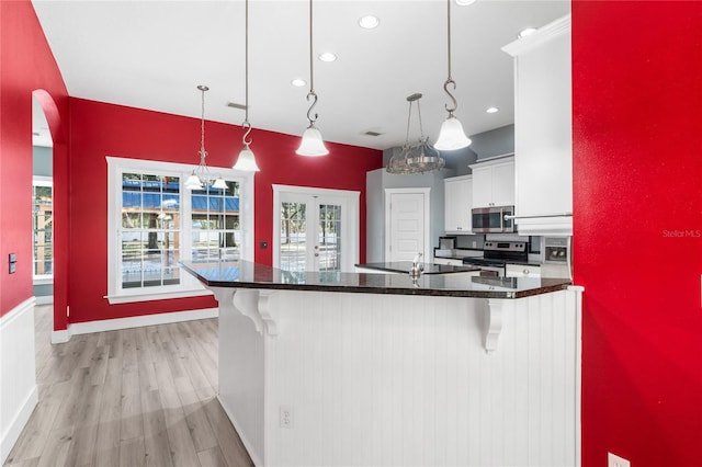 kitchen with a breakfast bar, stainless steel appliances, white cabinets, and hanging light fixtures