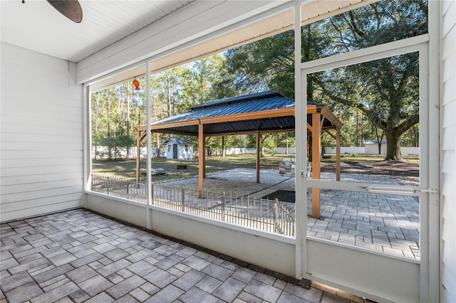 unfurnished sunroom featuring ceiling fan and a wealth of natural light