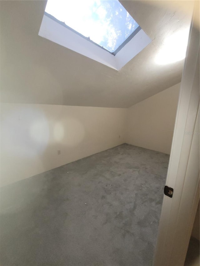 bonus room with vaulted ceiling with skylight and carpet floors