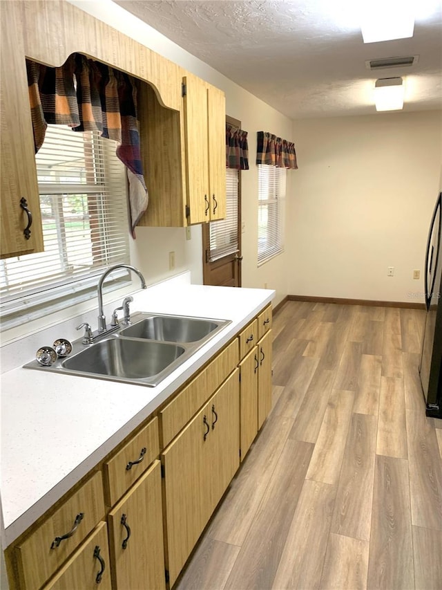 kitchen with sink, light hardwood / wood-style floors, fridge, a textured ceiling, and light brown cabinetry