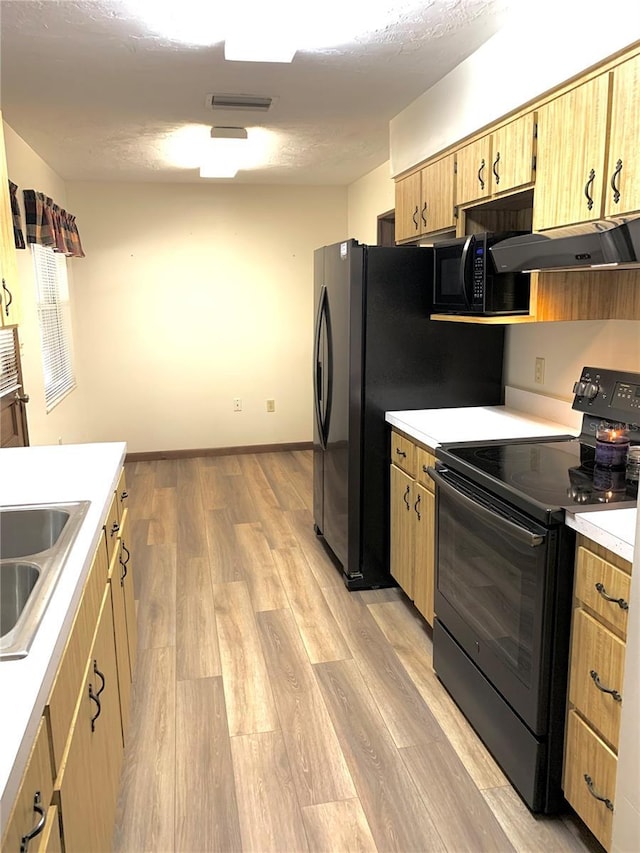 kitchen with black appliances, ventilation hood, sink, light brown cabinetry, and light hardwood / wood-style floors