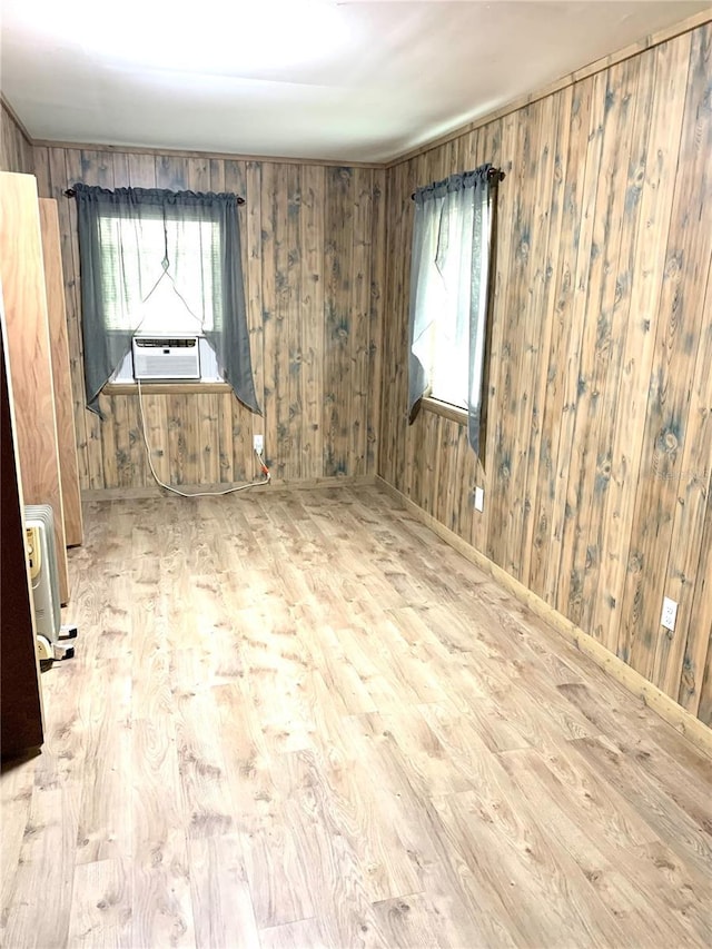 spare room featuring wood walls, a healthy amount of sunlight, and light wood-type flooring