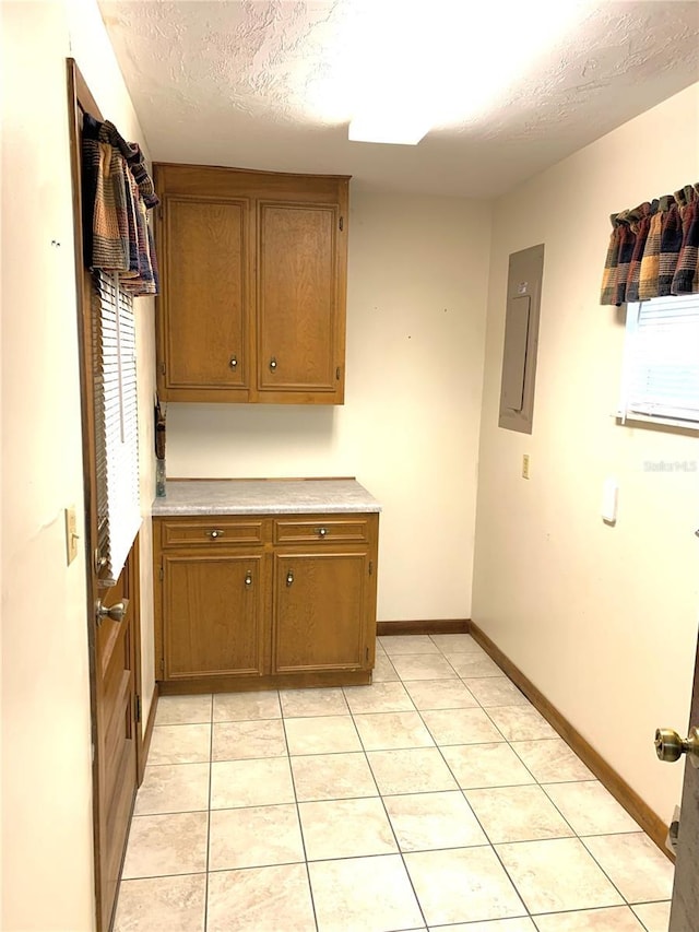 kitchen featuring light tile patterned flooring, a textured ceiling, and electric panel