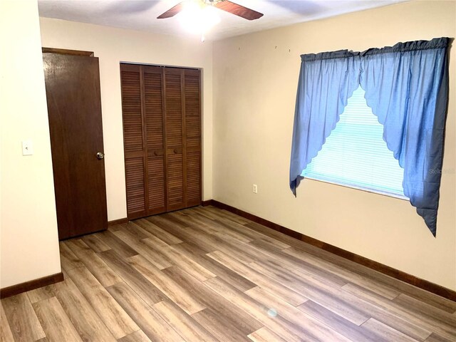 unfurnished bedroom featuring a closet, light hardwood / wood-style flooring, and ceiling fan