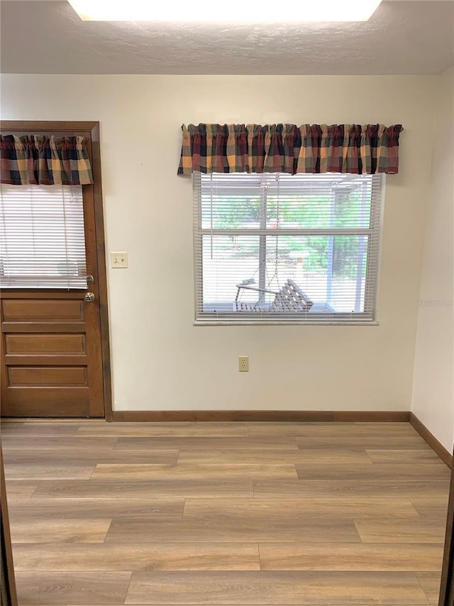 spare room with light hardwood / wood-style floors and a textured ceiling