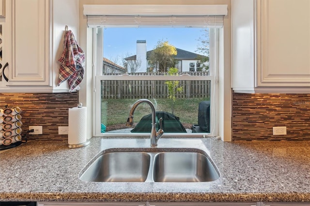 interior details featuring stone counters, decorative backsplash, and a sink