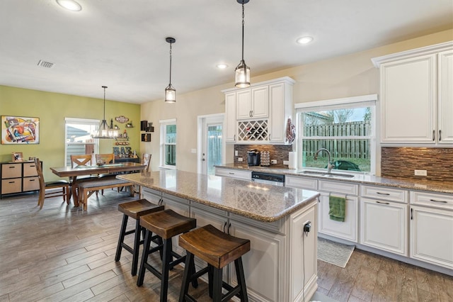 kitchen with sink, white cabinets, a center island, a breakfast bar area, and hanging light fixtures