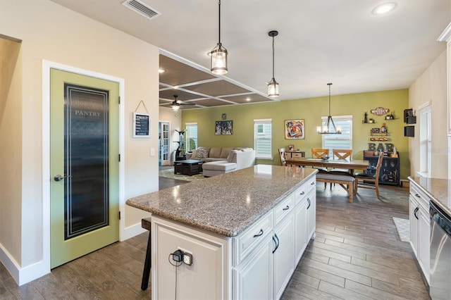 kitchen with white cabinets, ceiling fan with notable chandelier, stainless steel dishwasher, hanging light fixtures, and light stone countertops