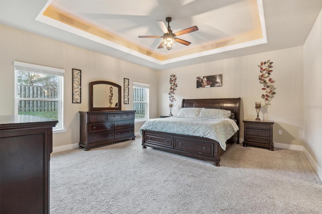 bedroom featuring carpet floors, a tray ceiling, and baseboards