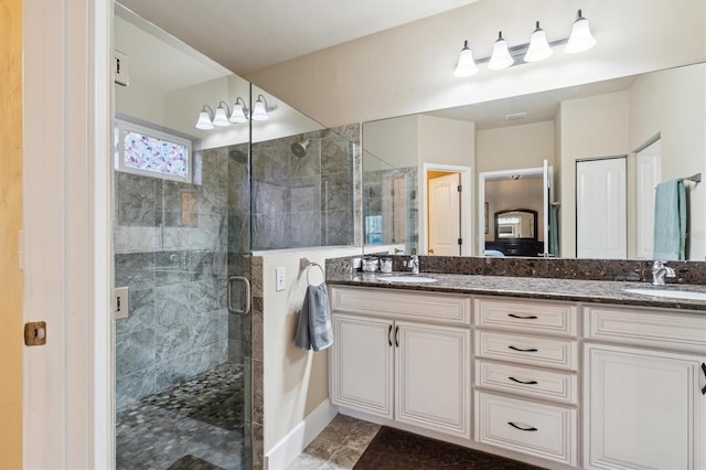 bathroom with double vanity, a shower stall, and a sink