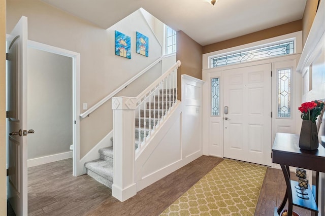 foyer with stairs, wood finished floors, and baseboards