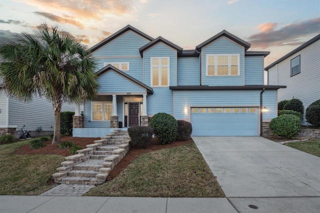 craftsman-style home with covered porch, an attached garage, stone siding, driveway, and a front lawn