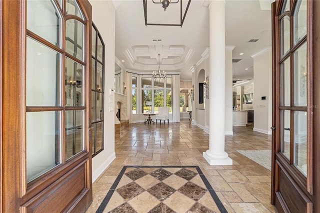 foyer entrance with ornate columns, french doors, a notable chandelier, a tray ceiling, and ornamental molding