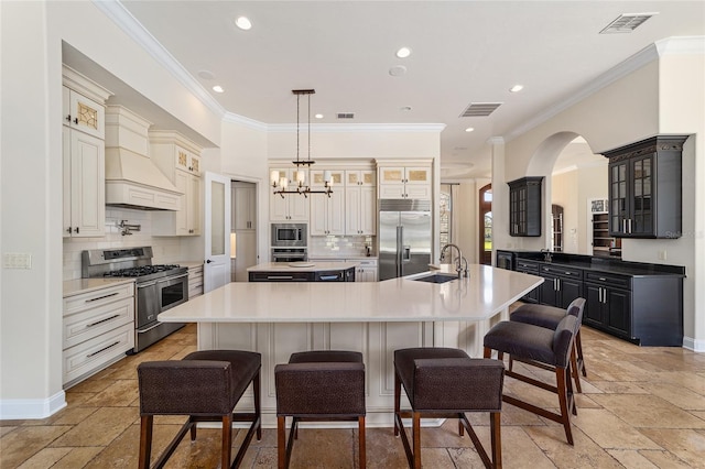 kitchen with built in appliances, a breakfast bar, a large island with sink, and sink