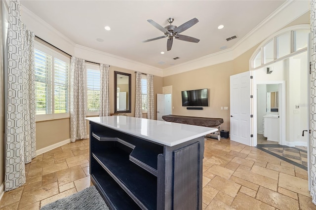 kitchen featuring ceiling fan, a center island, and crown molding