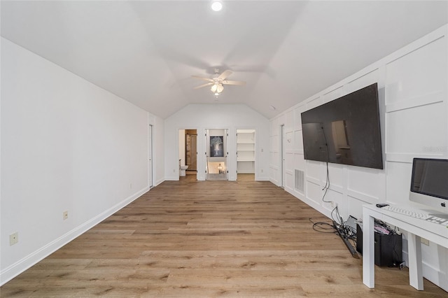 unfurnished living room with lofted ceiling, ceiling fan, light wood-type flooring, and built in shelves