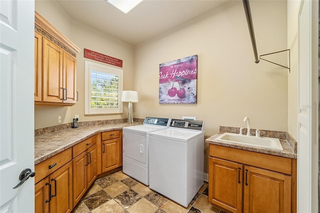 clothes washing area with cabinets, washing machine and dryer, and sink