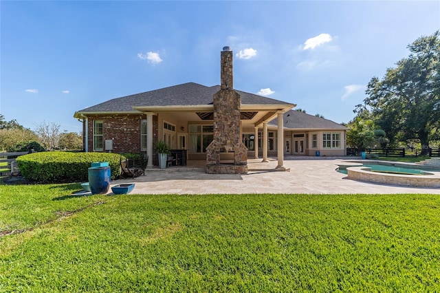 rear view of house featuring an in ground hot tub, an outdoor stone fireplace, a yard, and a patio area