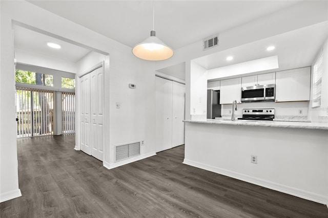 kitchen with white cabinetry, dark hardwood / wood-style flooring, kitchen peninsula, decorative light fixtures, and appliances with stainless steel finishes