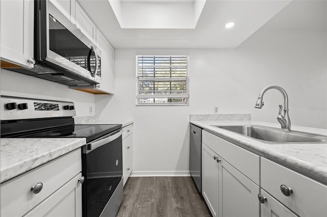 kitchen featuring sink, dark hardwood / wood-style flooring, light stone counters, white cabinetry, and stainless steel appliances