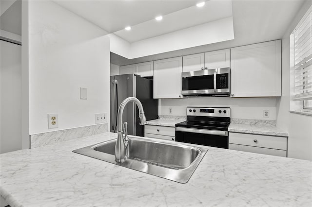 kitchen with light stone countertops, sink, white cabinets, and stainless steel appliances