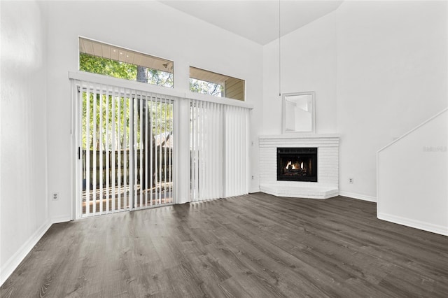 unfurnished living room featuring a fireplace, high vaulted ceiling, and dark wood-type flooring