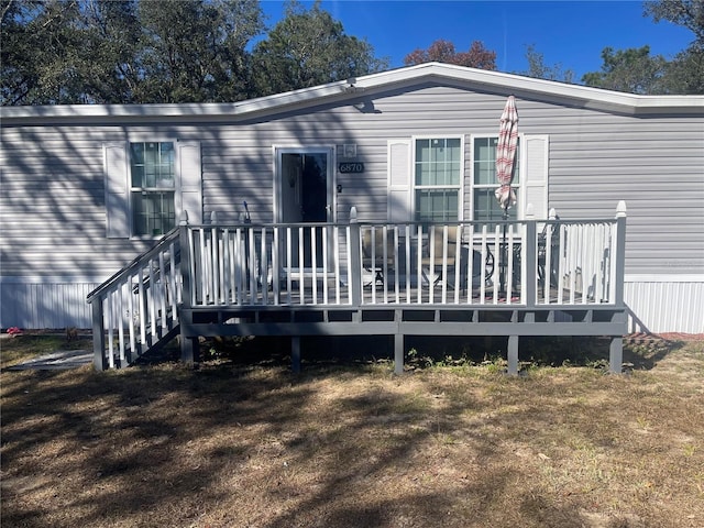 rear view of property featuring a lawn and a wooden deck