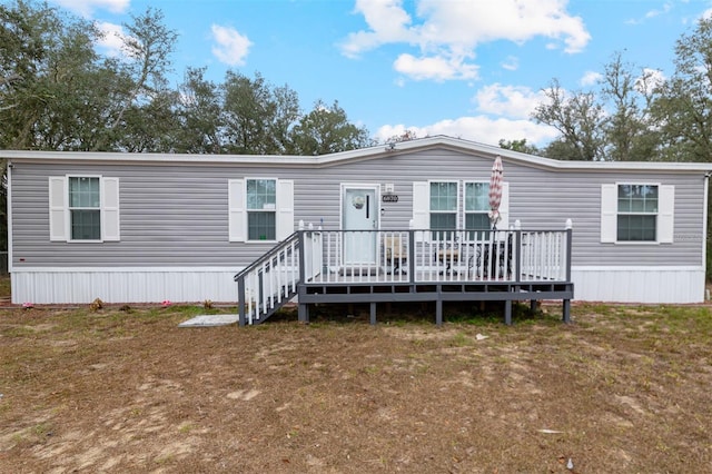 rear view of property featuring a lawn and a deck