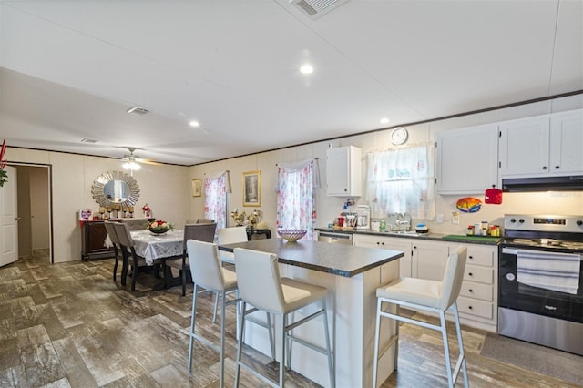 kitchen featuring a breakfast bar, a center island, dark hardwood / wood-style floors, appliances with stainless steel finishes, and white cabinetry