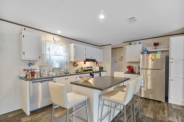 kitchen with white cabinets, crown molding, dark hardwood / wood-style floors, appliances with stainless steel finishes, and a kitchen island