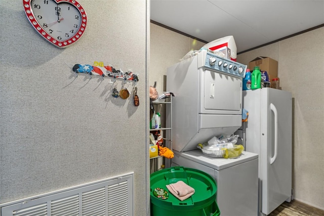 washroom featuring crown molding and stacked washer and dryer