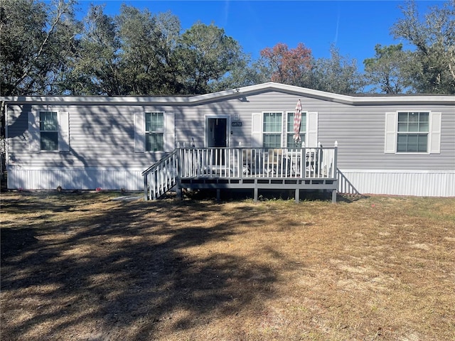 back of property with a wooden deck and a yard