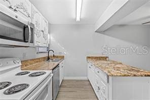 kitchen featuring white cabinetry, sink, wood-type flooring, and appliances with stainless steel finishes