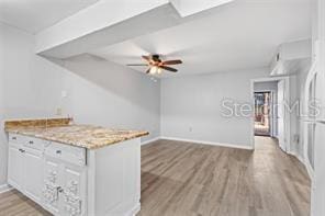 kitchen featuring white cabinets, ceiling fan, light stone countertops, and light wood-type flooring