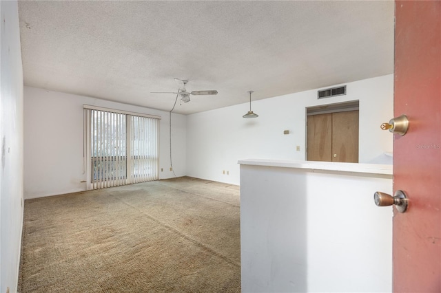 carpeted spare room with ceiling fan and a textured ceiling