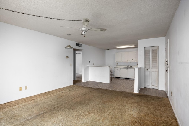 unfurnished living room with dark hardwood / wood-style floors, ceiling fan, and a textured ceiling