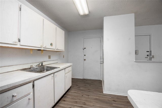 kitchen with white cabinets, a textured ceiling, dark wood-type flooring, and sink